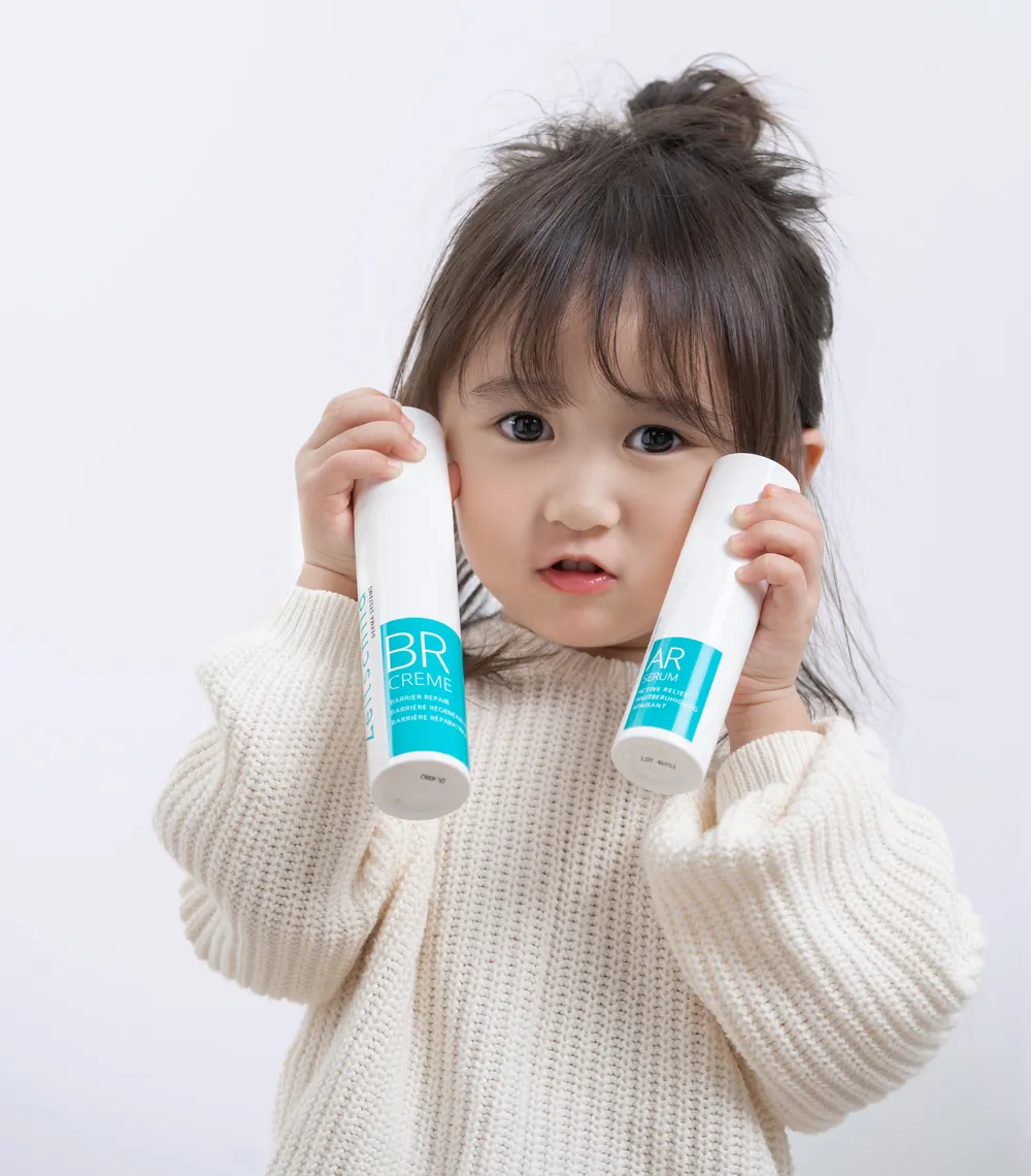 Young child holding Zeitschild BR Creme and AR Serum bottles